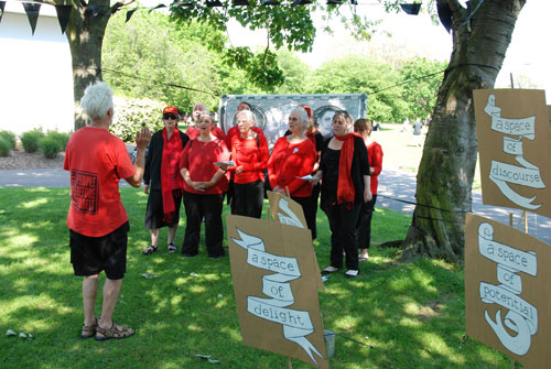 <p>The Strawberry Thieves Choir, with placards, banner and bunting by Rachael House, 2012.