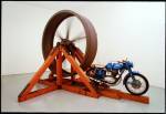 Chris Burden. The Big Wheel, 1979. Three-ton, eight-foot diameter, cast-iron flywheel powered by a 1968 Benelli 250cc motorcycle, 112 x 175 x 143 in (284.5 x 444.5 x 363.2 cm). Collection The Museum of Contemporary Art Collection, Los Angeles.