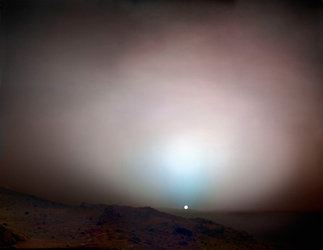 Sunset on Mars. Sunset colours on Mars in far cooler tones than those typically seen on Earth. The central blue glow is caused by sunlight scattering in the Martian atmosphere, the same phenomenon that makes Earth’s sky blue. Dust suspended in the atmosphere gives the rest of the sky a copper colour. Composite photograph. Spirit Rover, 19 May 2005. NASA/JPL/Michael Benson, Kinetikon Pictures. Courtesy of Flowers Gallery.