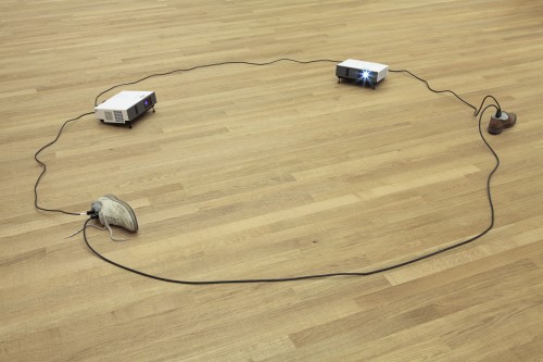 Paul Chan. Sock N Tease, 2013. Concrete, cord, shoes, and video projectors, with digital colour video, silent, 10.2 x 358.1 x 229.9 cm overall. Courtesy the artist and Greene Naftali, New York. © Paul Chan. Photograph: Tom Bisig, Basel.