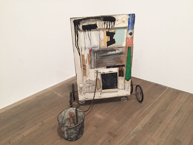 Robert Rauschenberg. Gift for Apollo, 1959. Oil paint, wood, fabric, newspaper, printed reproductions on wood with metal bucket, metal chain, door knob, L brackets, metal washer, nail and rubber wheels with metal spokes. 11.1 x 74.9 x 104.1 cm. The Museum of Contemporary Art, Los Angeles, The Panza Collection. Photograph: Martin Kennedy.