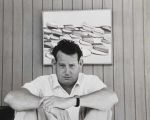 Wayne Thiebaud in his studio in Sacramento with his painting Pies in the background, 1961. Photo: Betty Jean Thiebaud. Collection of the Wayne Thiebaud Foundation. © Wayne Thiebaud/VAGA at ARS, NY and DACS, London 2025.